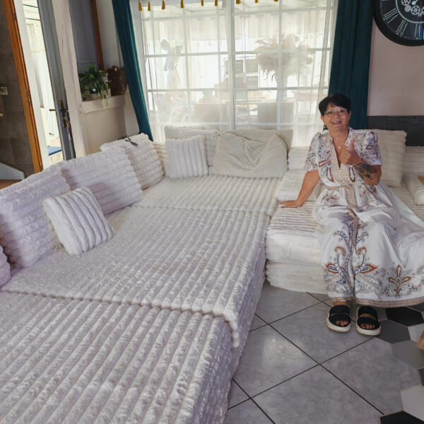 Satisfied French customer gives a thumbs‑up while sitting on large white fluffy modular compressed sofa at home